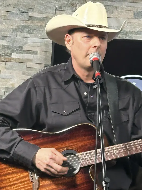 Fred Winston singing and playing acoustic guitar on stage